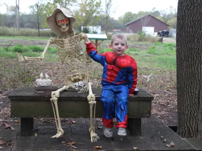 Kid posing with skeleton decoration at Haunted Walk event
